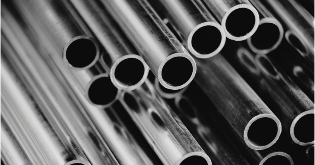 Close-up of stacked metal pipes with circular openings, showing smooth, reflective surfaces and an industrial setting.